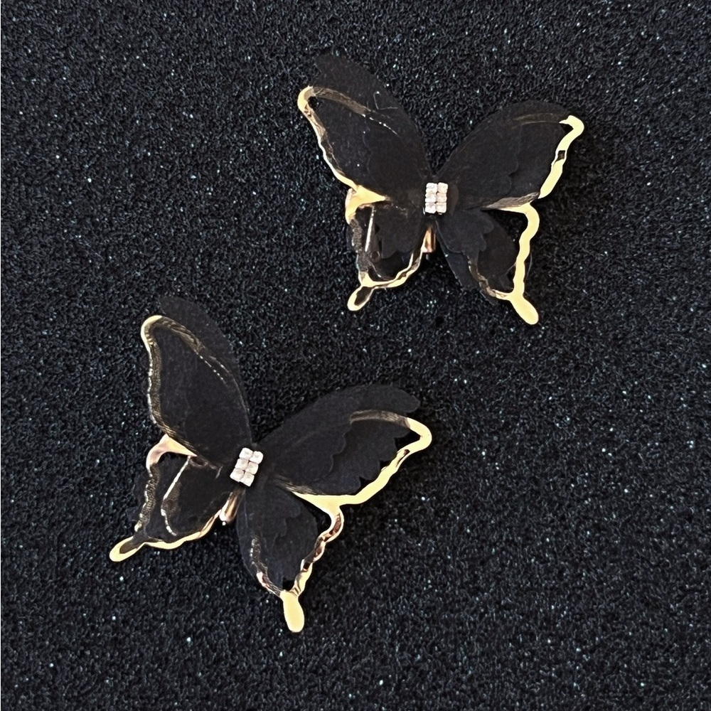 A pair of black golden butterfly clip-on earrings